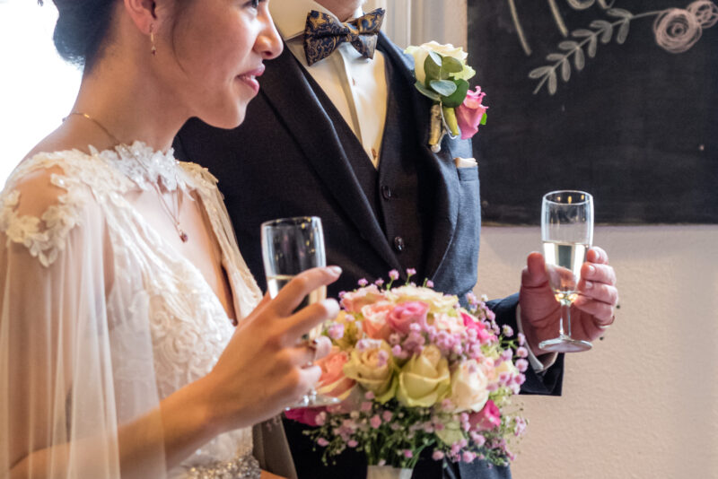 A natural wedding photographer capturing a bride and groom toasting with champagne in front of a chalkboard at a London wedding.