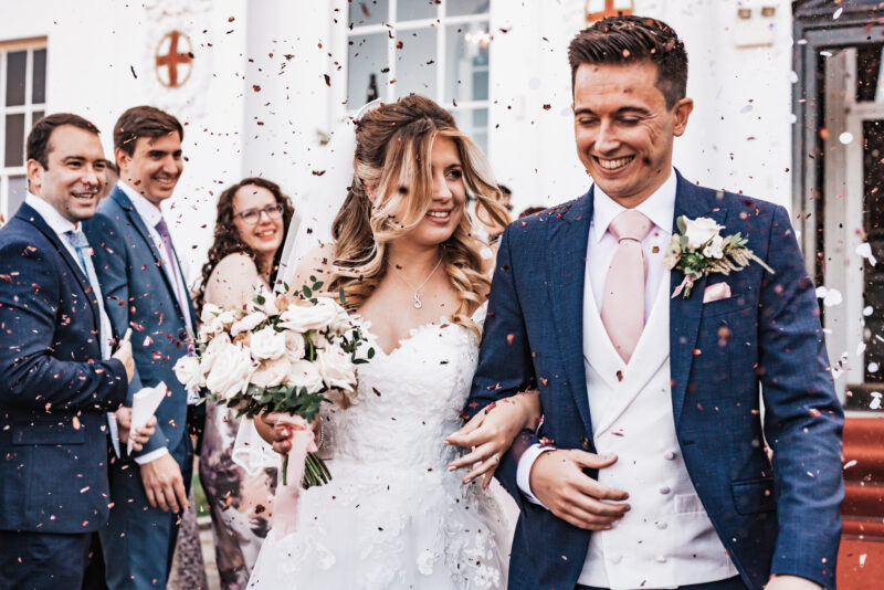 A bride and groom with confetti thrown at them.