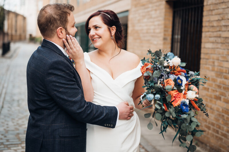 A bride and groom hugging on a cobbled street.