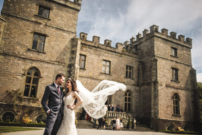 A bride and groom standing in front of a castle.
