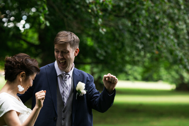 A bride and groom dancing in a park.