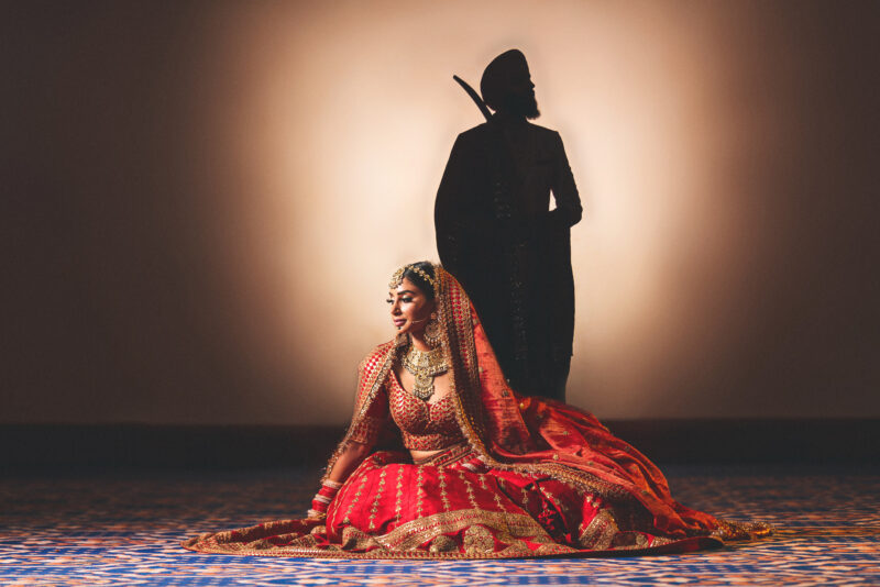 A bride and groom sitting on the floor in front of a shadow.