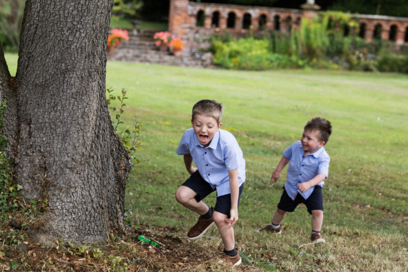 Two boys playing with a frisbee near a tree.