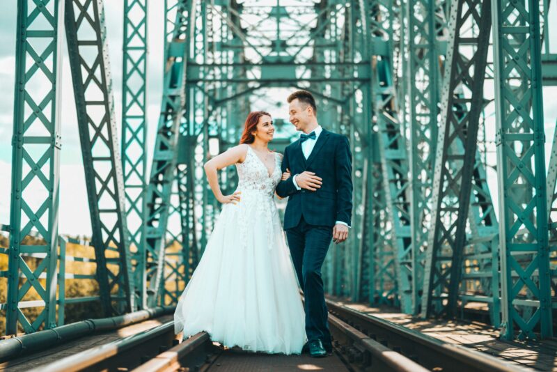 Bride and groom posing on a bridge.
