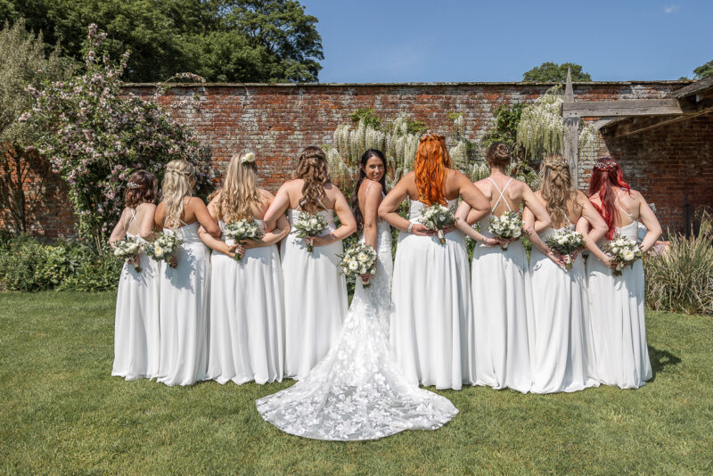 A group of bridesmaids standing in front of a brick wall.
