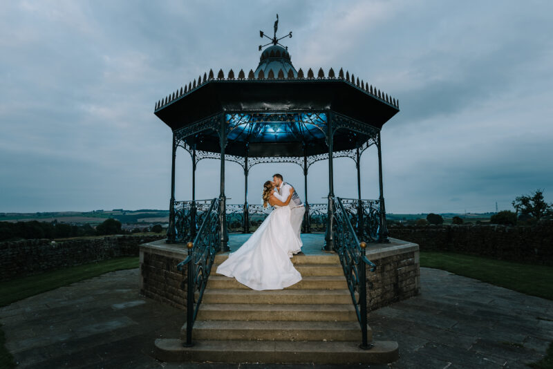 A bride and groom posing in front of a gazebo.
